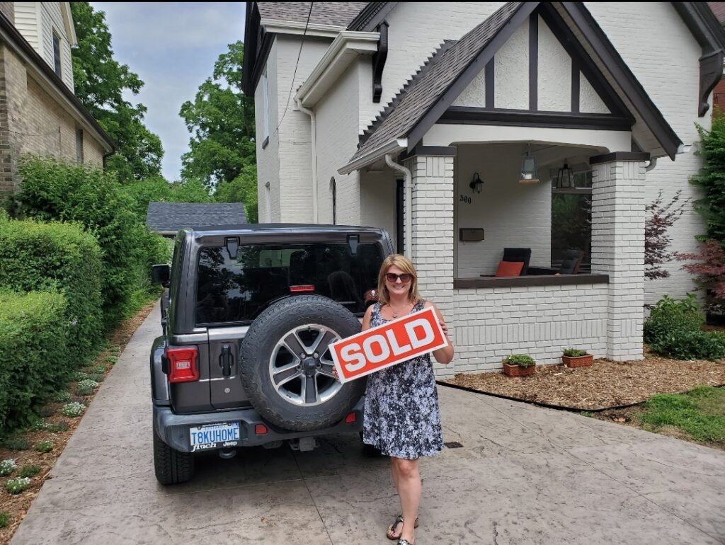 Woman with Sold Sign in front of new home